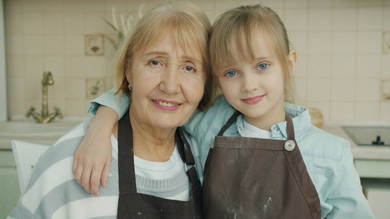 Une grand-mère et sa petite-fille en tablier dans une cuisine