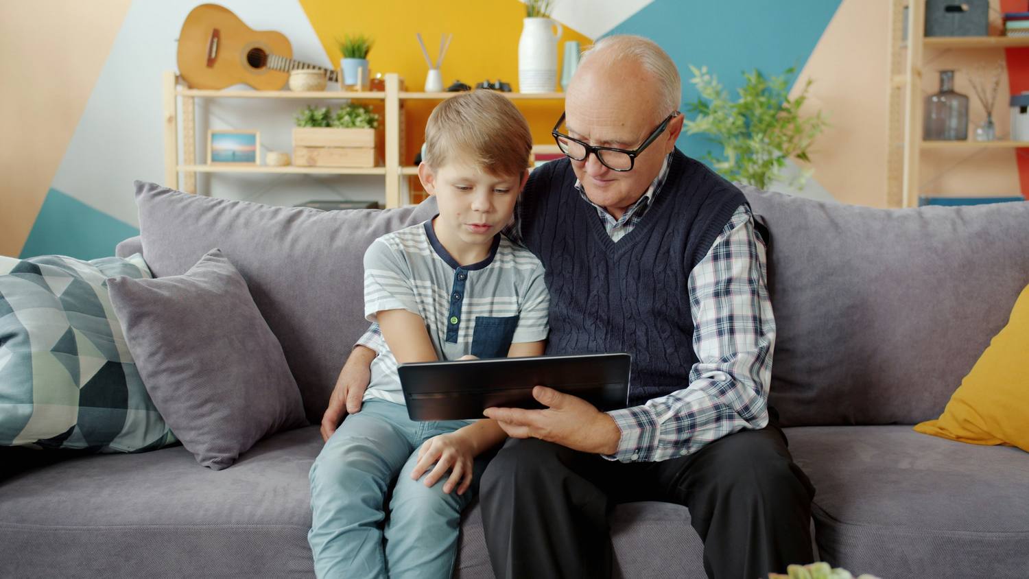 Un grand-père et son petit-fils regardant une tablette ensemble